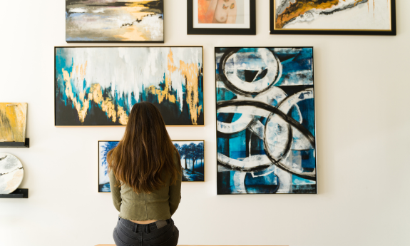 Lady sitting in front of paintings at an art gallery 