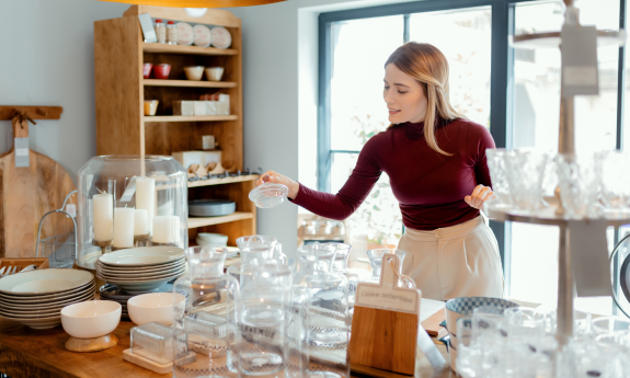 Lady setting up glasses at a home goods store 