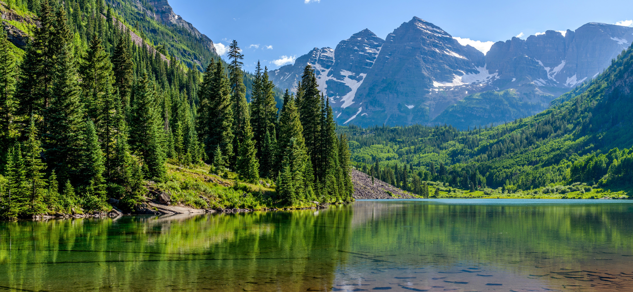 Iconic Maroon Bells mountain peaks towering over lush greenery during the summer season