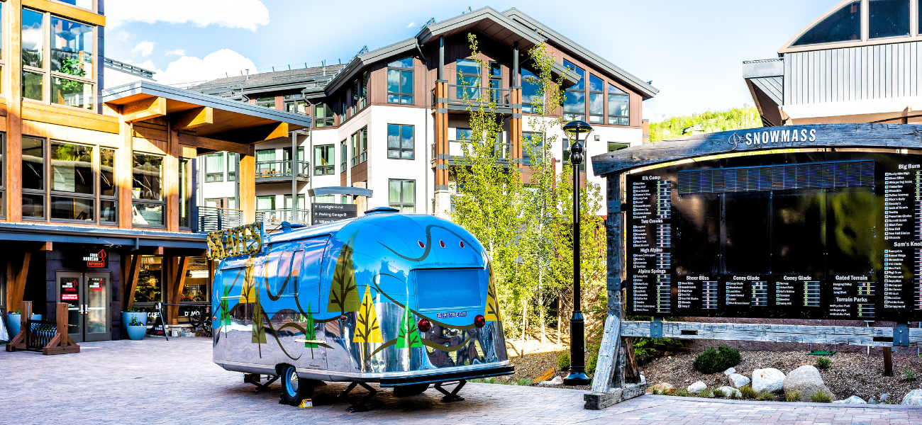 The vibrant base area of Snowmass Mountain in the summer, bustling with activities and surrounded by lush greenery